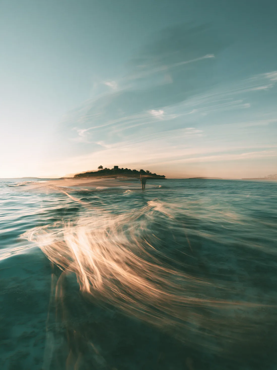 A dreamlike ocean with broad waves and hazy evening light